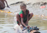 Petite fille indienne Laver les vêtements séchant au soleil chez les ghats à Varanasi, Inde . — Photo de stock
