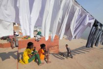 Bambini indiani e vestiti lavati che si asciugano alla luce del sole ai ghats a Varanasi, India . — Foto stock