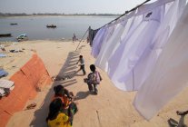 Enfants indiens et vêtements lavés séchant au soleil dans les ghats de Varanasi, Inde . — Photo de stock