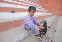 Porträt eines kleinen indischen Jungen und Hundes auf der Straße der Stadt. — Stockfoto