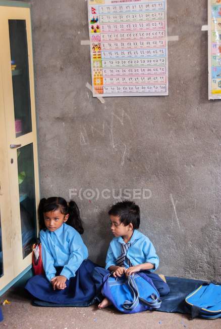 Niño y niña sentado en el aula de la escuela - foto de stock