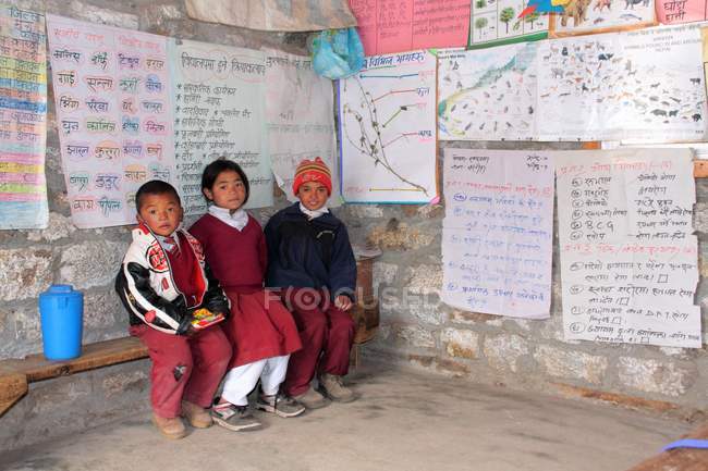 Niños y niñas en uniformes sentados en el aula - foto de stock