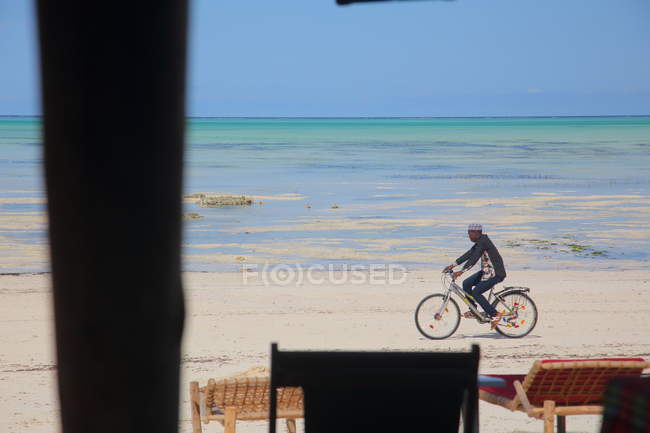 Hombre montar en bicicleta en la playa Zanzíbar - foto de stock