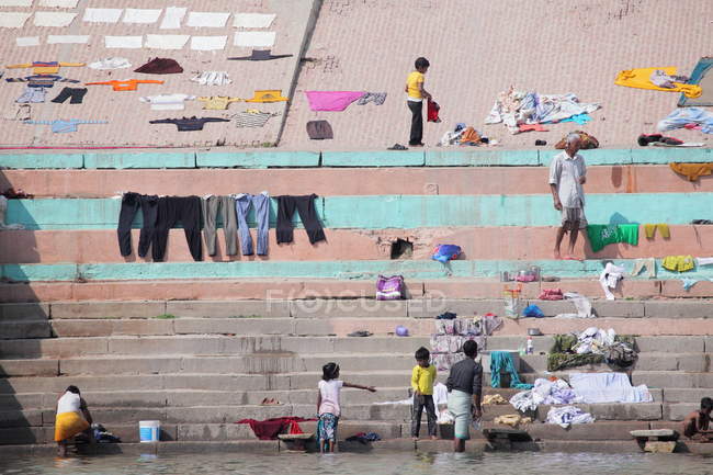 Personas y ropa lavada secándose a la luz del sol en los ghats en Varanasi, India . - foto de stock