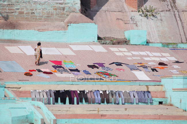 Indische Frau und gewaschene Kleidung beim Trocknen im Sonnenlicht in den Ghats in Varanasi, Indien. — Stockfoto