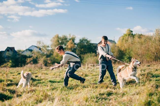 Dos hermanos gemelos con perros husky - foto de stock