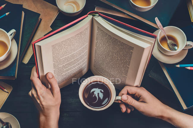 Mãos com livro aberto e copo — Fotografia de Stock