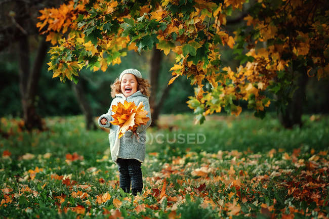Lachendes Mädchen mit orangefarbenen Blättern — Stockfoto