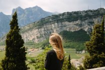 Jovem mulher olhando para montanhas rochosas — Fotografia de Stock