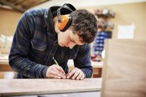 Mann markiert ein Stück Holz — Stockfoto