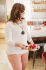 Woman carrying a plate with fresh raspberries — Stock Photo