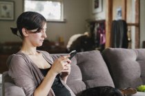 Woman on the sofa using her smart phone — Stock Photo