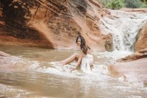 Frau sitzt auf einem Felsen in einem Fluss. — Stockfoto