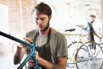 Hombres en un taller de reparación de bicicletas - foto de stock