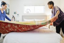 Two women making up a bed — Stock Photo