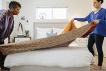 Две женщины заправляют постель — стоковое фото