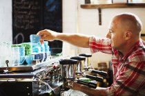 Homme travaillant sur une machine à café — Photo de stock