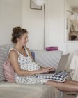 Femme enceinte utilisant un ordinateur portable — Photo de stock