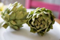 Two artichokes lying on a table. — Stock Photo