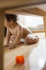 Baby boy sitting under table. — Stock Photo