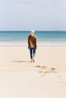Mulher andando descalça em uma praia — Fotografia de Stock