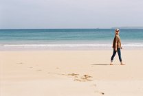 Женщина ходит босиком по пляжу — стоковое фото