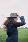 Frau im Wind hält ihren Hut. — Stockfoto