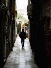 Man walking down a narrow alleyway — Stock Photo