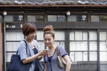 Japonais les femmes regardant cellulaire . — Photo de stock