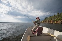 Человек рыбачит с лодки — стоковое фото