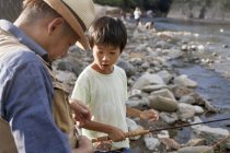 Padre e hijo pescando junto a un arroyo . - foto de stock