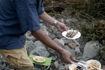 Uomo con in mano un piatto di pesce alla griglia — Foto stock