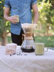Man standing at a table, making coffee. — Stock Photo