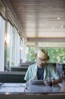 Людина використовує цифровий планшет, сидячи в їдальні — стокове фото