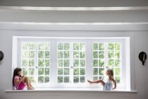 Girls playing by a large window. — Stock Photo