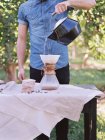 Hombre de pie en una mesa, haciendo café . - foto de stock