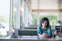 Frau blickt auf ihr Smartphone an einem Tisch — Stockfoto