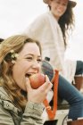 Женщина, кусающая красное яблоко — стоковое фото