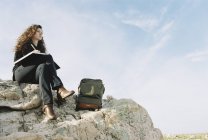 Mujer sentada en una roca con bloc de notas - foto de stock