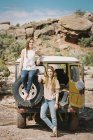 Mujeres de pie junto al jeep en la carretera de montaña - foto de stock