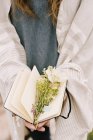 Frau hält Notizbuch mit Wildblumen in der Hand — Stockfoto