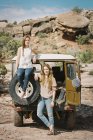 Women standing by jeep on mountain road — Stock Photo