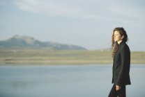 Donna in piedi sulla riva di un lago . — Foto stock