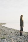 Mujer de pie en la orilla de un lago . - foto de stock