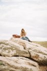 Donna seduta su una roccia — Foto stock