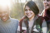 Women and man smiling in sunlit forest — Stock Photo