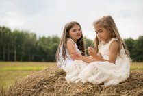 Girls sitting on haystack playing. — Stock Photo