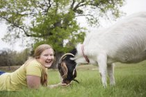 Mädchen liegt mit Ziege im Gras — Stockfoto