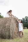 Girls playing by a large haybale — Stock Photo