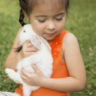 Criança segurando coelho branco — Fotografia de Stock